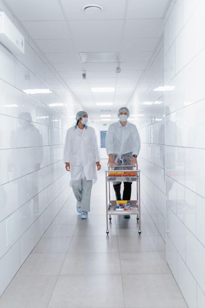 Two healthcare professionals in PPE walking through a laboratory corridor, carrying samples.